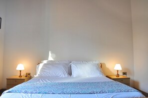 A hotel room with a bed, two bedside lamps, and a patterned bedspread.