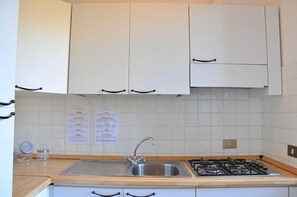 A kitchen with white cabinets, a stainless steel sink, and a gas stove.