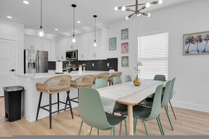 A modern kitchen with white cabinets, a stainless steel refrigerator, and a black and white tiled backsplash.