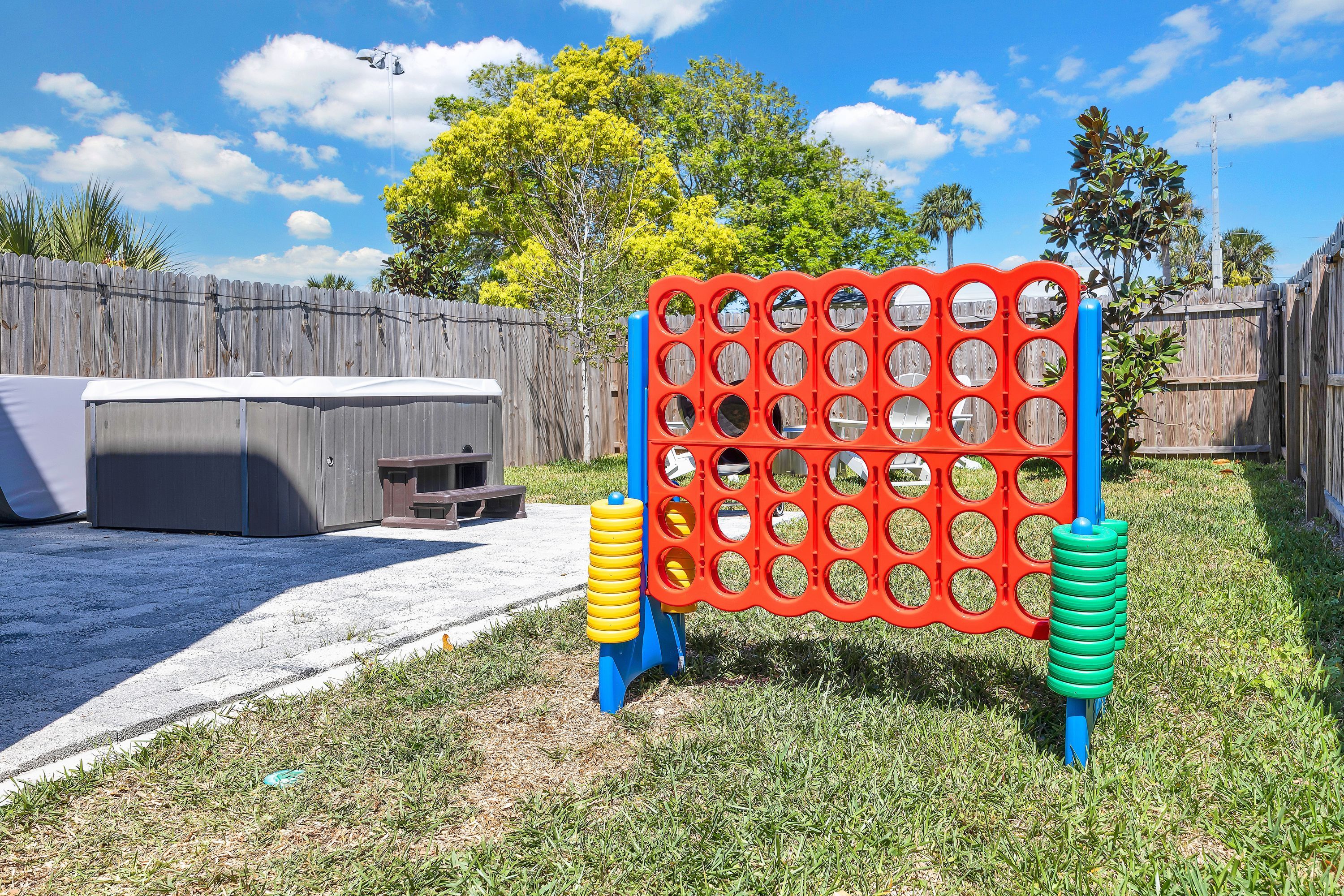 A backyard with a wooden fence, a hot tub, and a colorful game board.