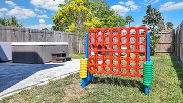 A backyard with a wooden fence, a hot tub, and a colorful game board.