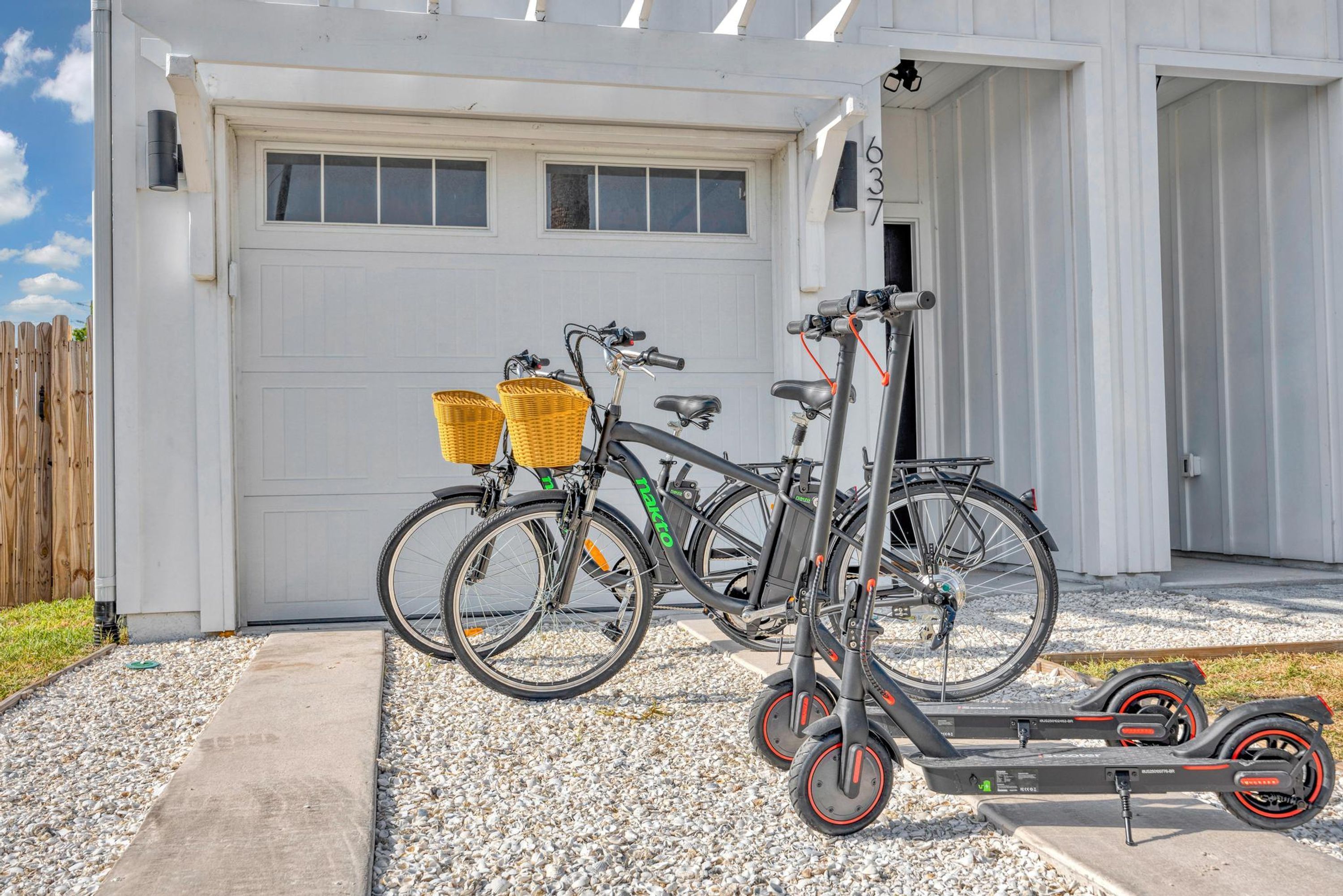 A garage with two bicycles and an electric scooter parked outside.