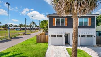 A two-story house with a garage, a well-maintained lawn, and a palm tree.