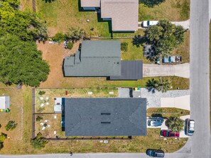 Vista aérea de una zona residencial con varias casas, una calle pavimentada y automóviles estacionados.