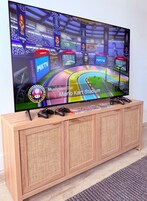 Un televisor mostrando un juego de Mario Kart, montado sobre un mueble de madera con un panel frontal tejido.