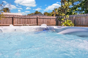 A hot tub with a wooden fence and trees in the background.