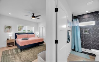 Quarto moderno com cama, mesa de cabeceira e ventilador de teto.