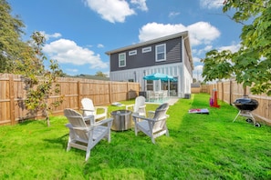 A backyard with a wooden fence, a barbecue grill, and outdoor seating with chairs and a table. - Beach Home Hot Tub · Sauna · Arcade · Bikes · 9BR (Jacksonville Beach)