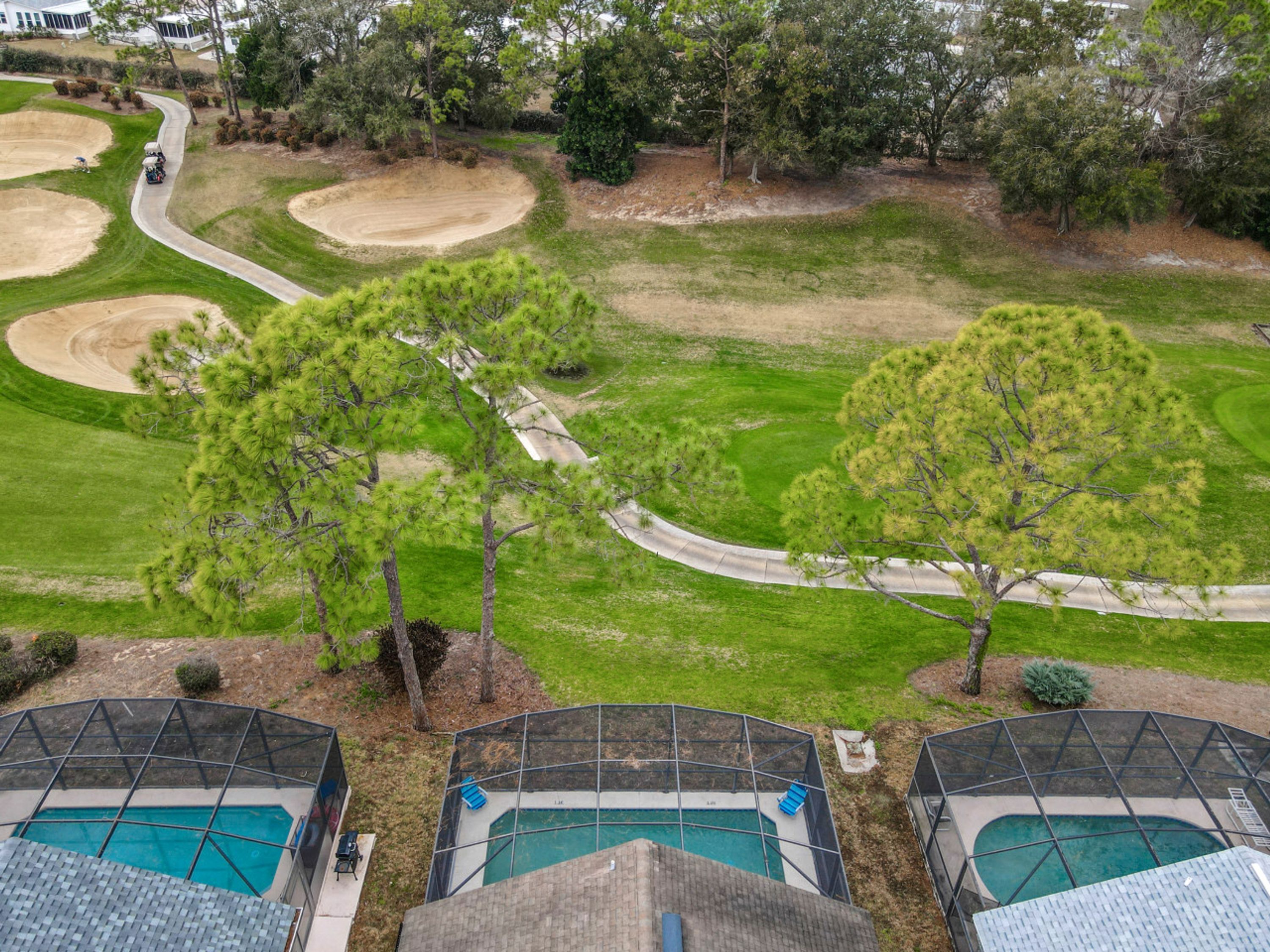 A residential area with a golf course, swimming pools, and a view of the surrounding landscape.
