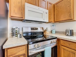 A kitchen with wooden cabinets, a stainless steel stove, a microwave, a toaster, and a blender.