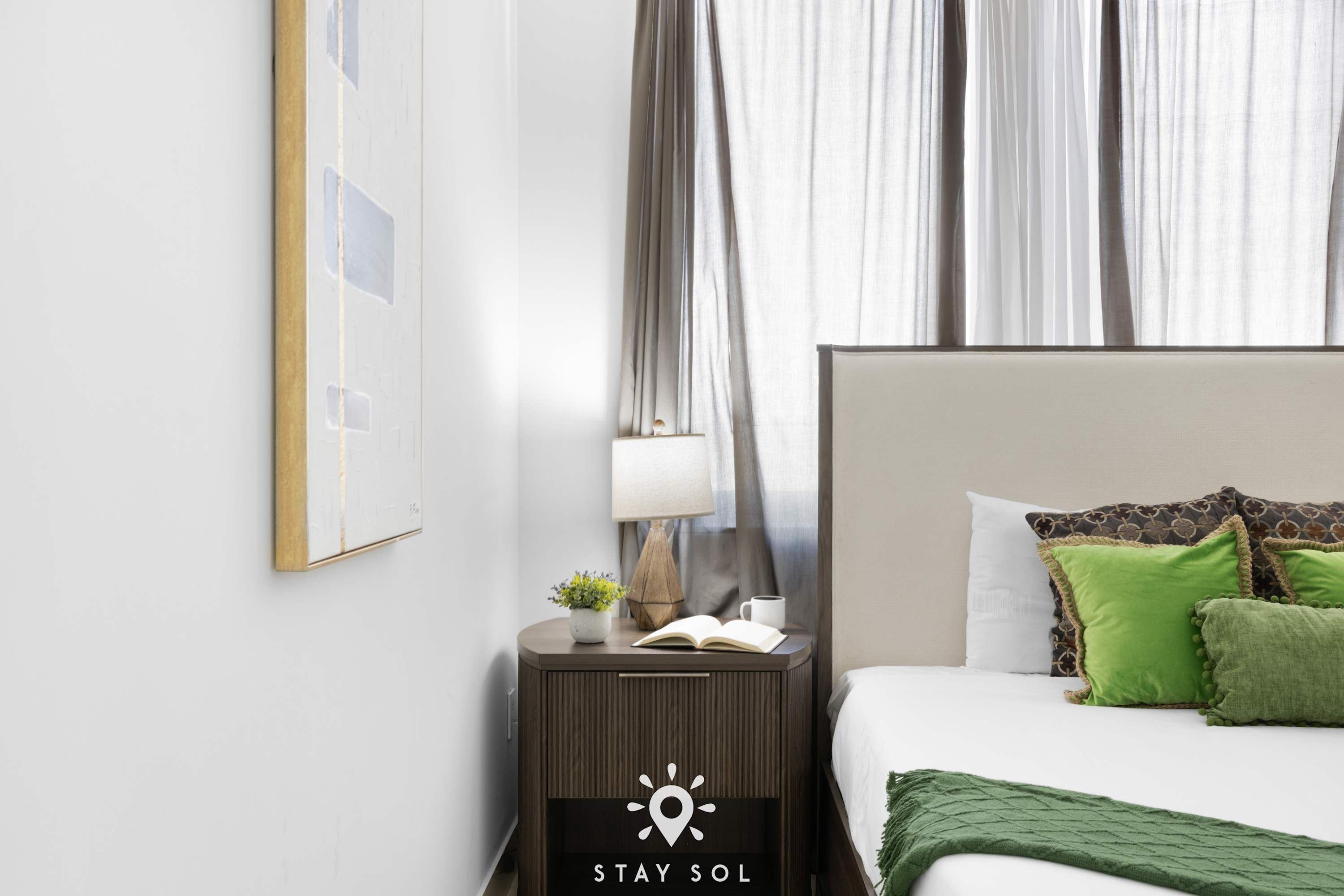 A hotel room with a bed, a nightstand, a lamp, and a framed picture on the wall.