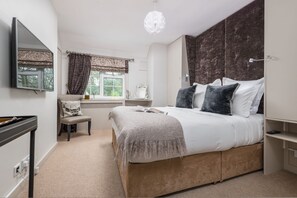 A bedroom with a bed, a chair, a desk, a window with curtains, and a wall-mounted TV. - The Fox at Hurley - Stunning Boutique B B (Maidenhead)