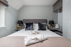 A neatly made bed with a folded towel, two pillows, and a book on the bed. - The Fox at Hurley - The Warren Suite (Maidenhead)