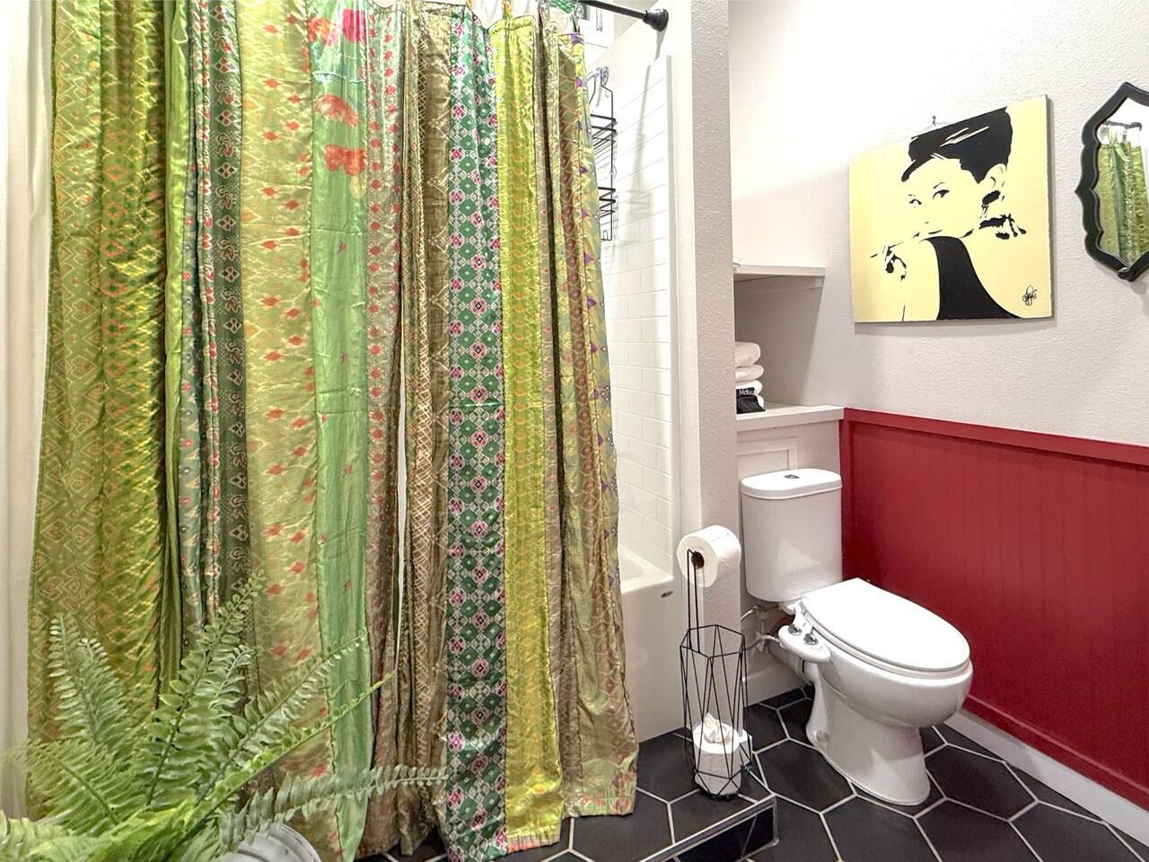 A bathroom with a shower curtain, toilet, and a wall-mounted toilet paper holder.