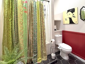 Een badkamer met douchegordijn, toilet en een toiletrolhouder op de muur.