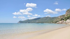 Una playa con agua cristalina, una orilla arenosa y una montaña al fondo.