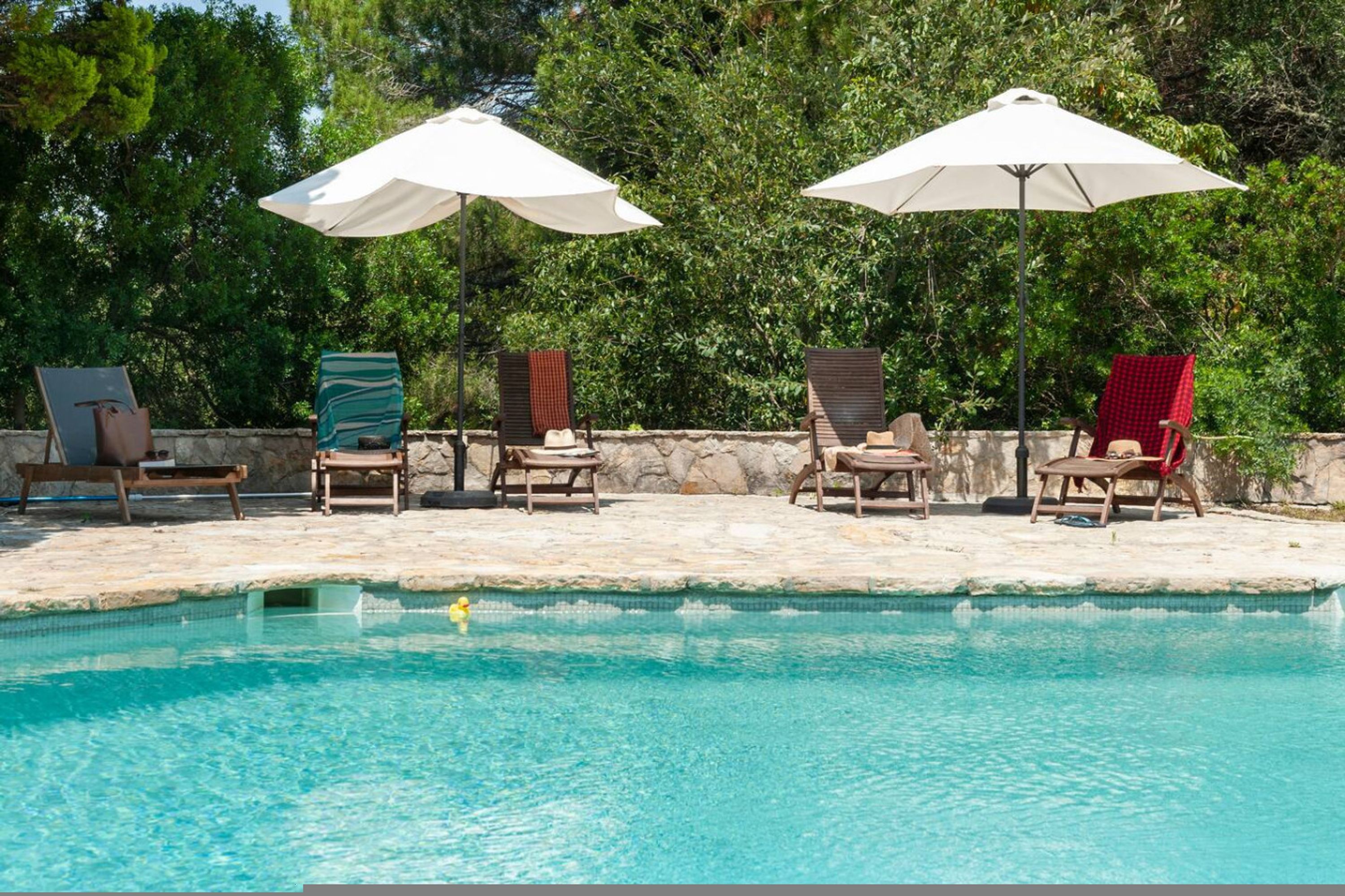 Zona de piscina con sillas de descanso y sombrillas.