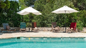 Zona de piscina con sillas de descanso y sombrillas.