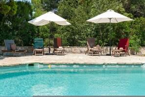 Área de piscina com espreguiçadeiras e guarda-sóis.