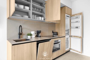 A modern kitchen with wooden cabinets, a built-in oven, a coffee maker, and a dishwasher. - Work Relax With Rooftop Retreat 1br-2ba Miami (Miami)