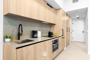 Eine moderne Küche mit Holzausstattung, einem Edelstahl-Spülbecken und einem Einbauofen.