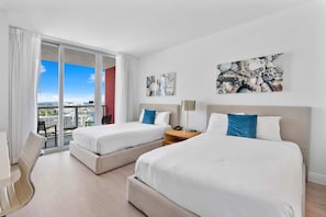 Quarto de hotel com duas camas, uma escrivaninha e uma cadeira.