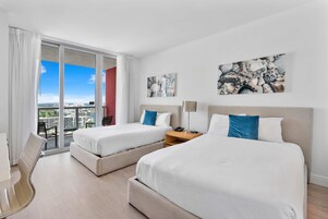 A hotel room with two beds, a desk, and a chair.