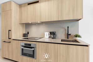 A modern kitchen with wooden cabinets, a Bosch oven, a coffee maker, and a sink. - Rooftop Sunsets in Modern 1BR in Downtown (Miami)