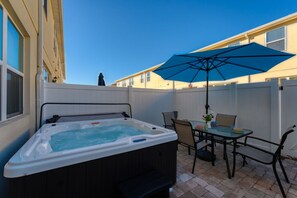A backyard with a hot tub, patio furniture, and a blue umbrella. - Magic Retreat Hot Tub Game Room Near Disney (Kissimmee)
