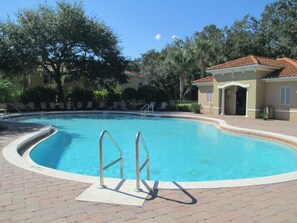 A swimming pool with a curved edge, surrounded by a brick walkway. - Magic Retreat Hot Tub Game Room Near Disney (Kissimmee)