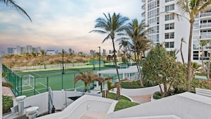 A tennis court surrounded by palm trees and a high-rise building. - Oceanview Studio Pool Beach Dining Miami (Sunny Isles Beach)
