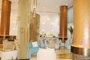 Een ruime lobby met een bar, zitgedeelte en decoratieve details.