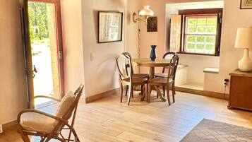 Una habitación con techo de madera, una mesa de comedor con sillas, un otoman decorado y un ventanal con vistas.