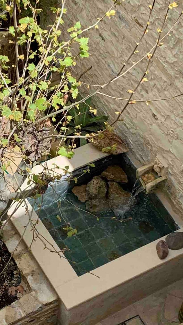 A small outdoor water feature with a stone basin and a waterfall. - Place of Grace in Lefkara (Pano Lefkara)