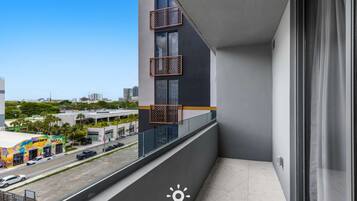 Edifício moderno com varanda, vista para a rua com carros estacionados e fachada colorida.