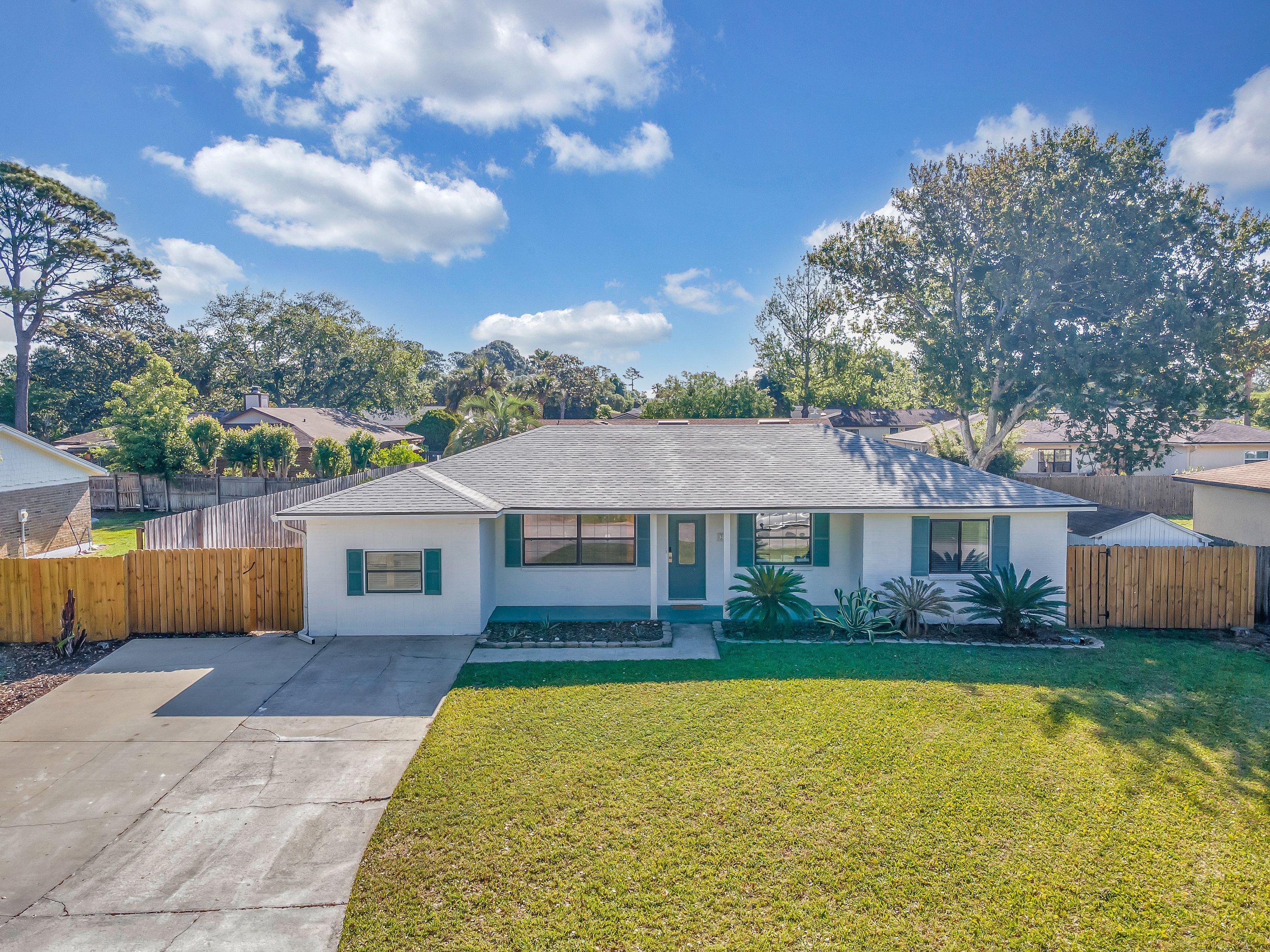 A single-story house with a front yard, a wooden fence, and a clear sky.