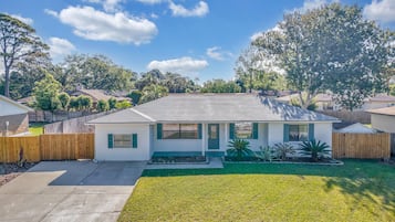A single-story house with a front yard, a wooden fence, and a clear sky.