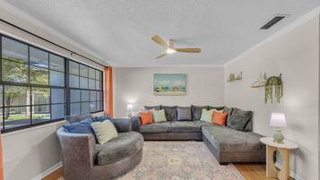 Een moderne woonkamer met een hoekbank, een ronde fauteuil en een kamerbreed tapijt met een patroon.