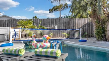 Ein Schwimmbecken mit Holzterrasse, Liegestühlen und einem bunten Schwimm-Entchen.