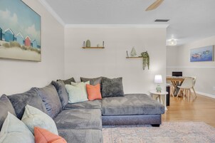 Una sala de estar moderna con un sofá modular, una mesita auxiliar y un comedor con mesa y sillas.