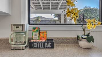 Un espacio de café con una cafetera, cápsulas de café y un cartel.