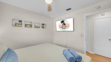 Een slaapkamer met een bed, een plafondventilator, een tv aan de muur en een deur.