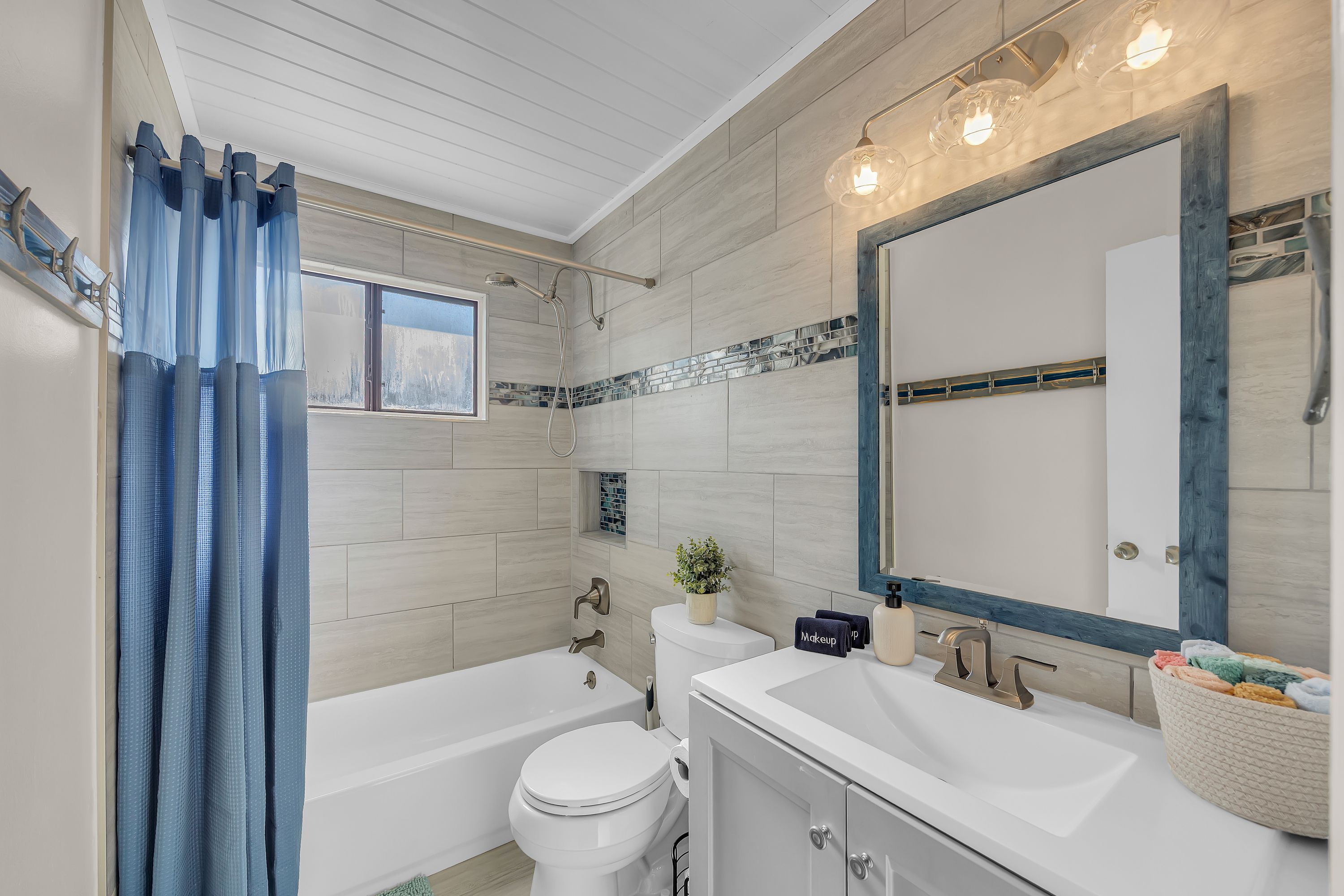 Un baño con bañera, inodoro, tocador y un espejo grande.