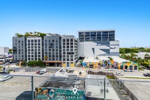 A modern building with multiple floors, a parking lot, and a colorful mural on the side. - Wynwood Escape Stylish Studio With Balcony in Miami (Miami)