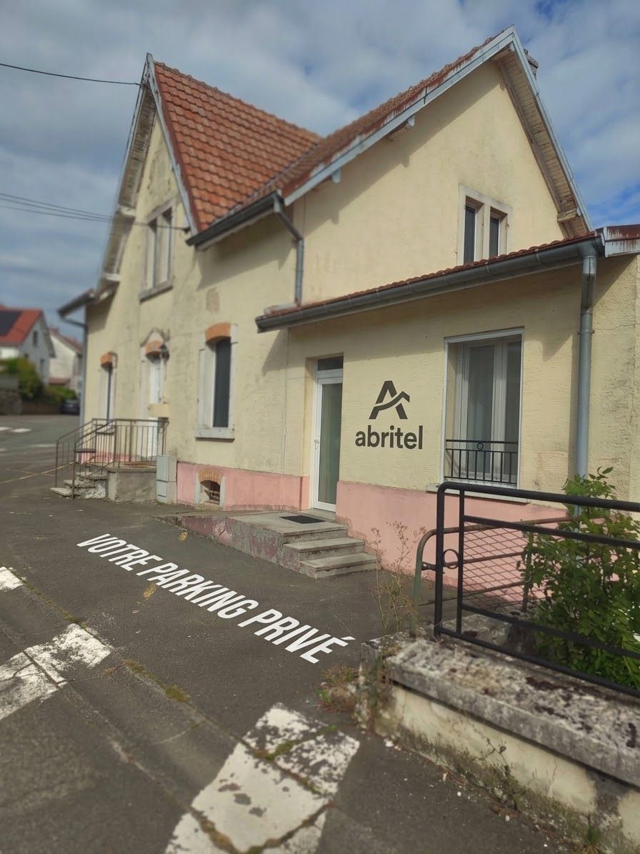 Een gebouw met een bord waarop 'abritel' staat en een parkeerbord dat 'JE PARKEERPLAATS' aangeeft, aan de straat.
