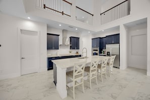 A modern kitchen with a central island, dark cabinets, and a two-tiered balcony.
