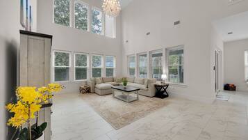 A spacious living room with a sectional sofa, a coffee table, and a chandelier.