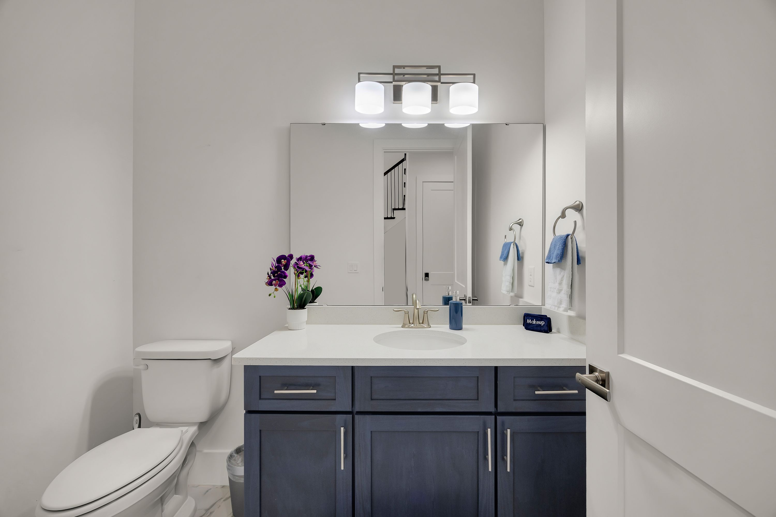 A modern bathroom with a toilet, sink, and dark cabinets.