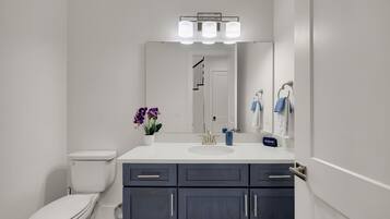 A modern bathroom with a toilet, sink, and dark cabinets.