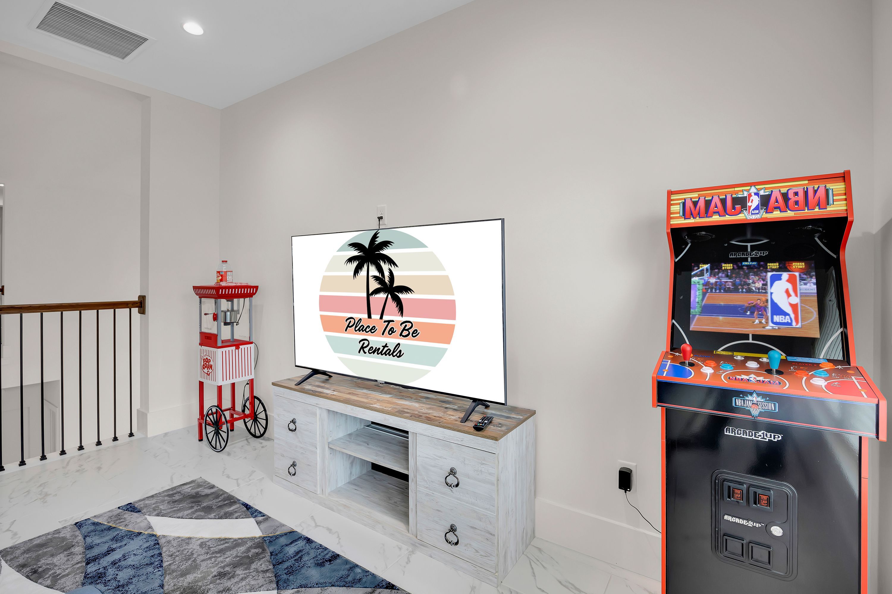 A living room with a flat-screen TV, a popcorn machine, and an arcade game machine.